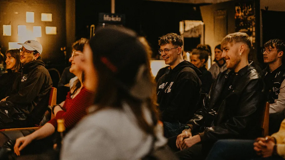 Smiling audience members at an indoor event.