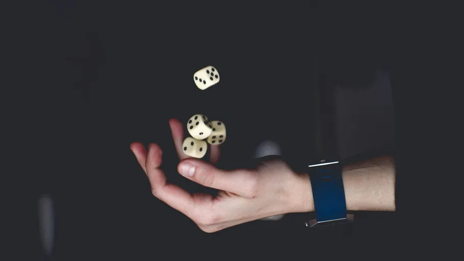 Hand wirft Würfel in die Luft.