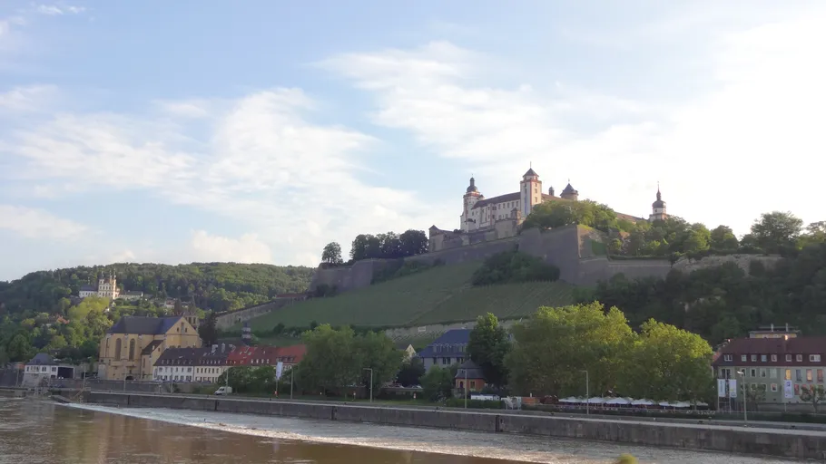 Burg auf Hügel mit Fluss und Dorf.