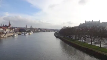 River with boats, city skyline, and hill in background.
