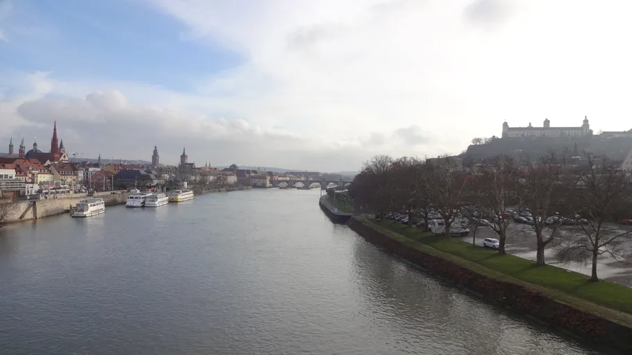 Fluss mit Booten, Stadtansicht und Hügel im Hintergrund.