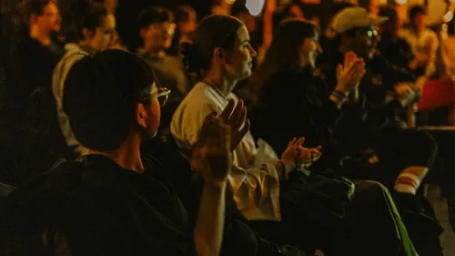Audience clapping in dimly lit room.