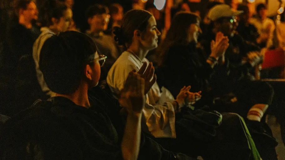 Audience clapping in dimly lit room.