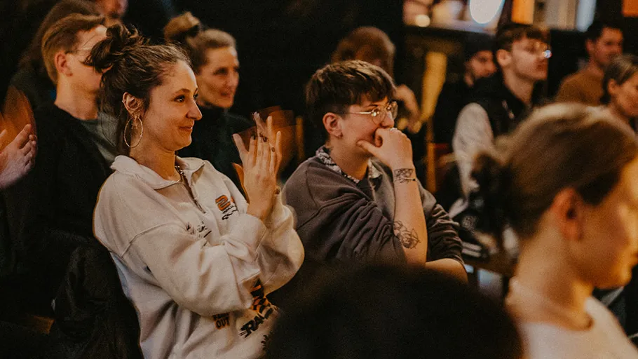 People sitting and clapping in an audience.