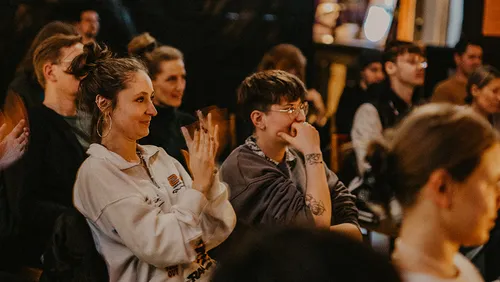 People sitting, clapping in a crowded room.
