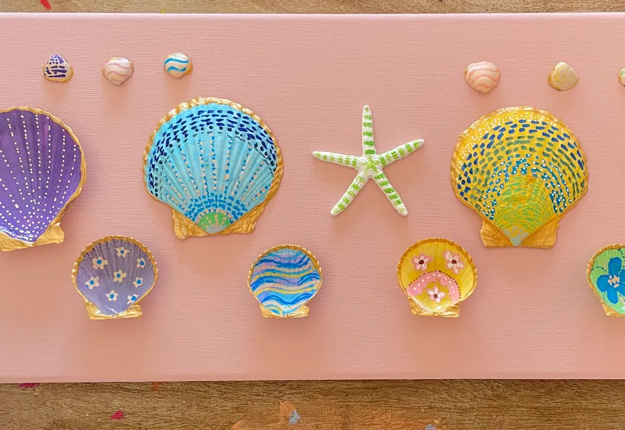 Colorful seashells and starfish on pink canvas.