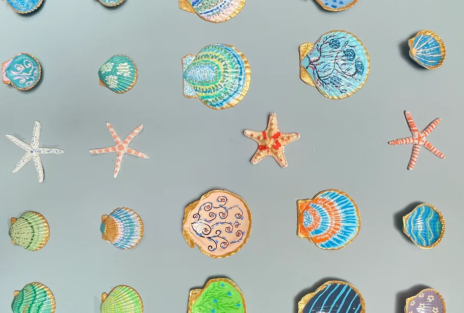 Bunte bemalte Muscheln und Seesterne auf grauem Hintergrund.