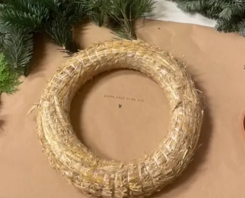 Straw wreath with pine branches on table.