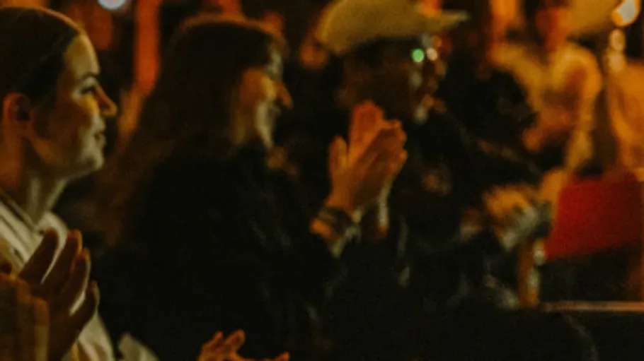 People clapping at a dimly lit event.