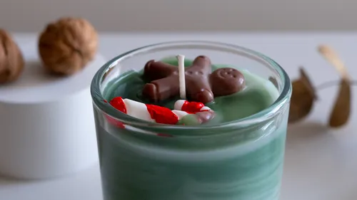 Green candle with decorations in glass jar.