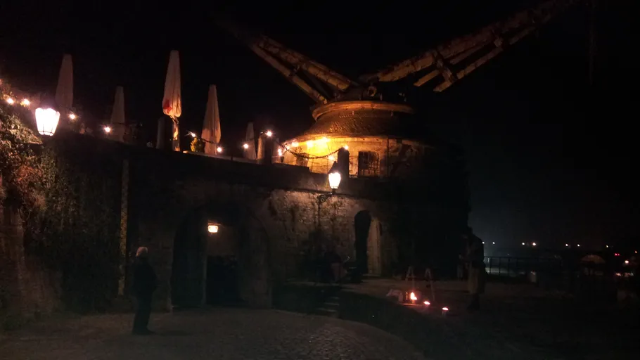 Historischer Kran beleuchtet bei Nacht, Flussansicht.