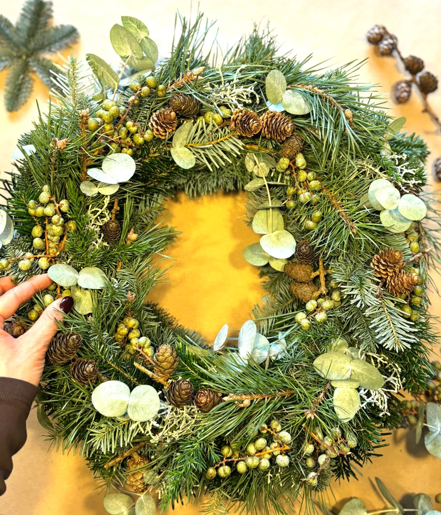Hand adjusting a decorative green wreath.