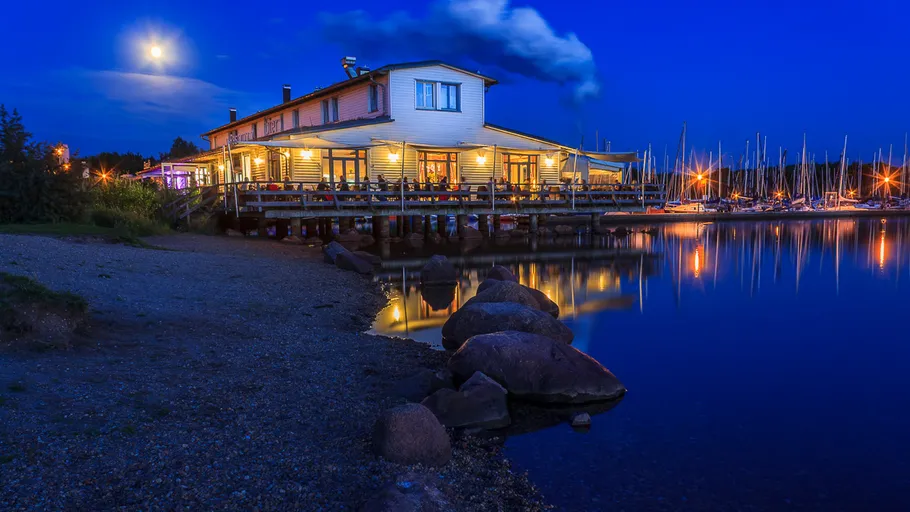 Am Meer beleuchtetes Restaurant bei Nacht.