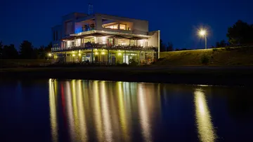 Illuminated building reflecting in night waters.