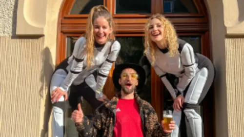 Two women and a man posing outside a building.