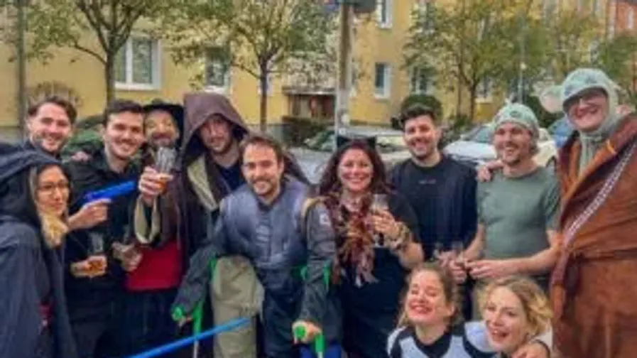 Gruppe von Menschen in Kostümen im Freien, lächelnd.