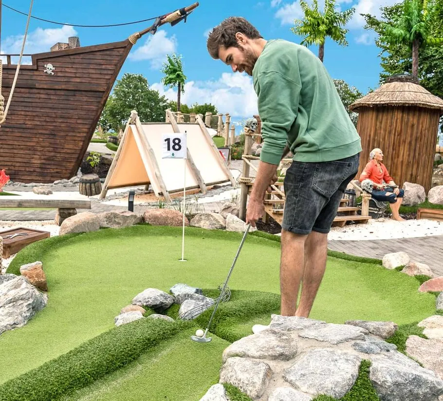 Man playing mini golf on rocky course.