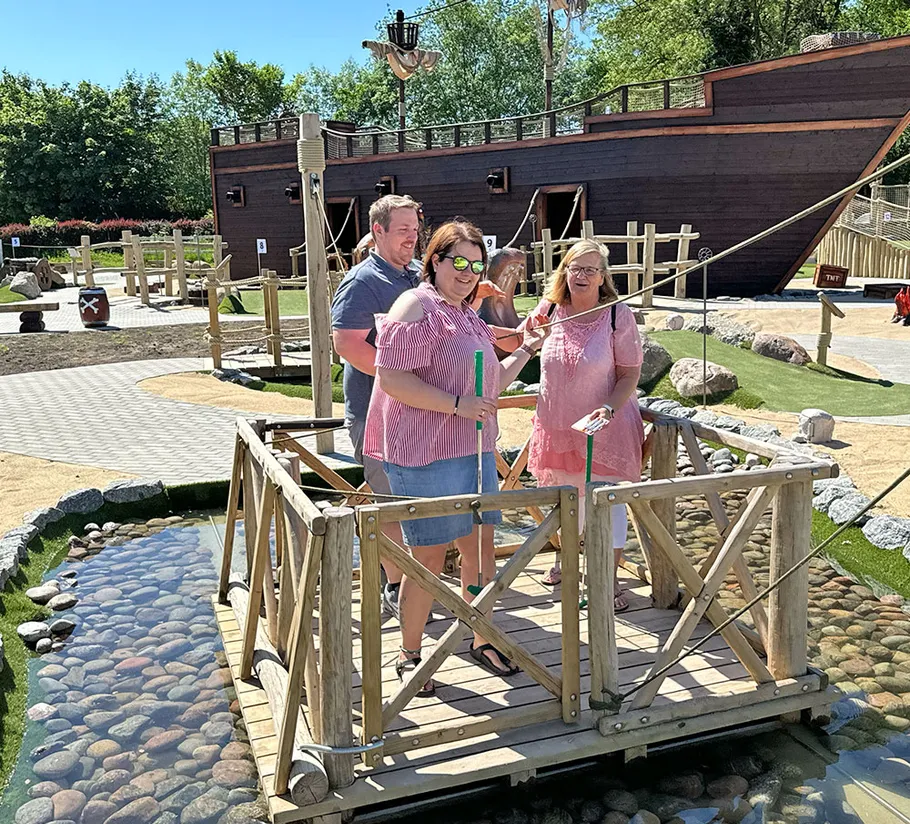 Three people on mini-golf course bridge.