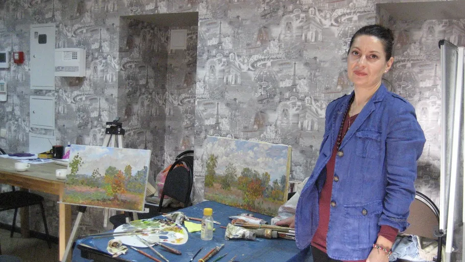 Woman standing near table with paintings.