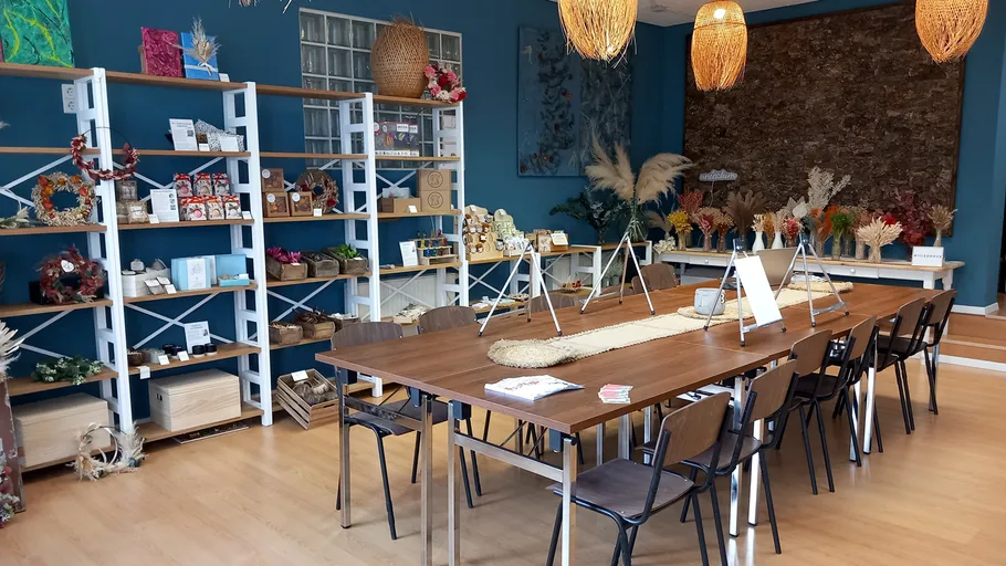 Bastelstudio mit Tisch, Stühlen und Regalen.