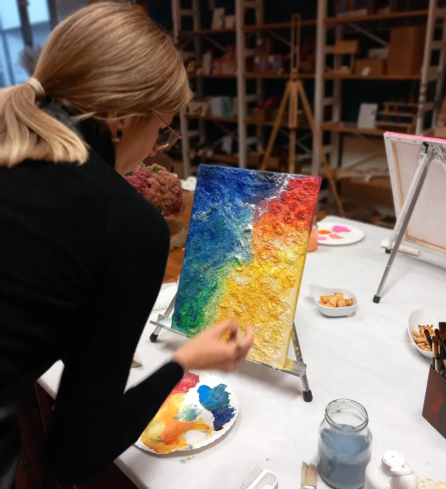 Woman painting colorful abstract artwork in studio.