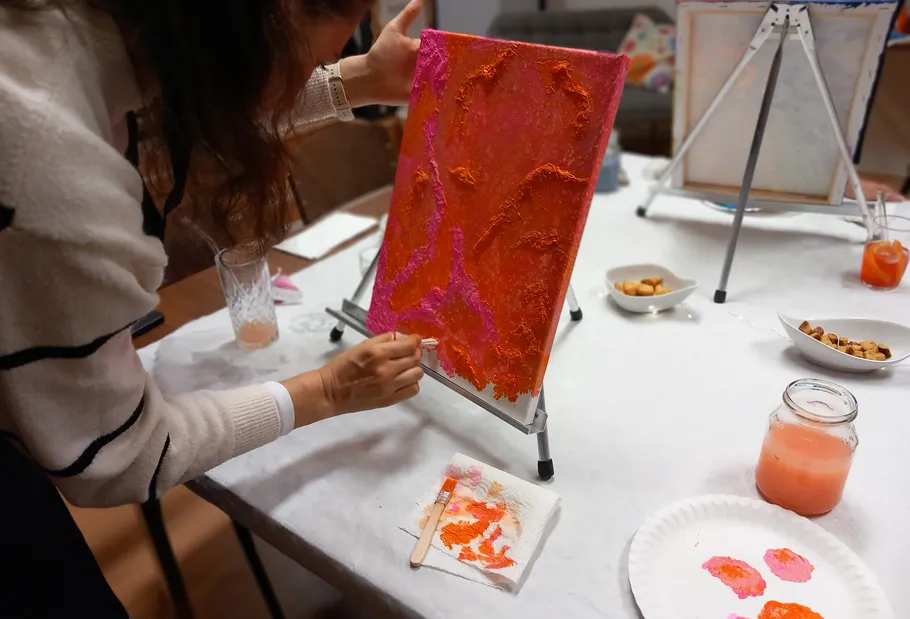 Person painting abstract art on small canvas.