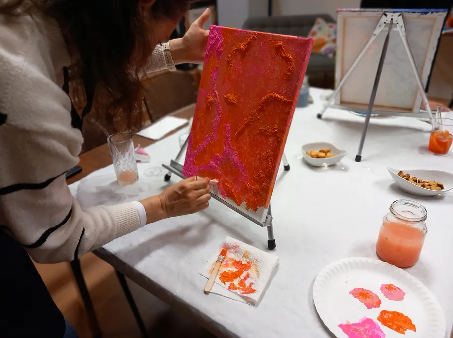 Person painting colorful canvas at indoor table.