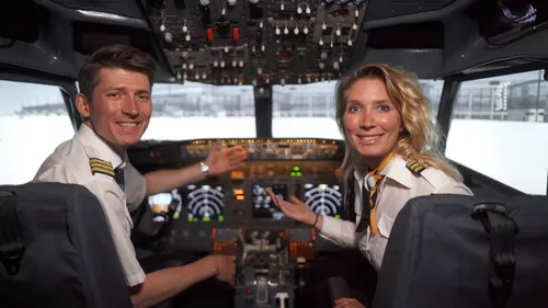 Two pilots smiling in aircraft cockpit.