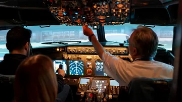 Pilots operating airplane cockpit, focused environment.