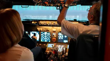 Pilots in cockpit operating an airplane.