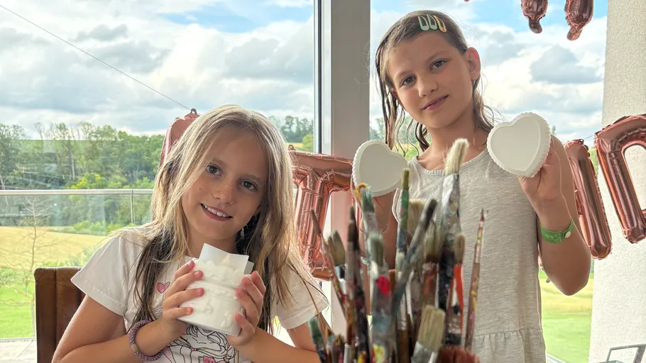 Two girls holding ceramic items indoors.