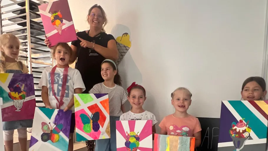 Kinder halten bunte Gemälde im Klassenzimmer hoch.