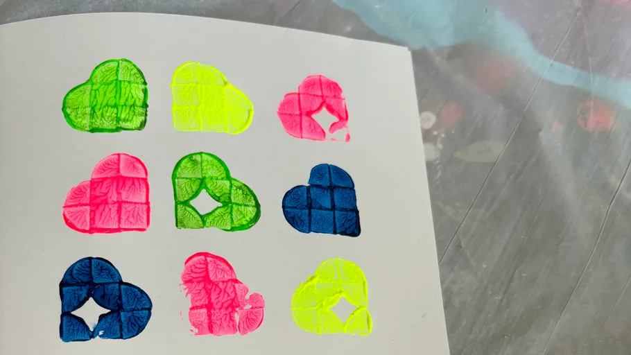 Nine colorful heart stamps on white paper.