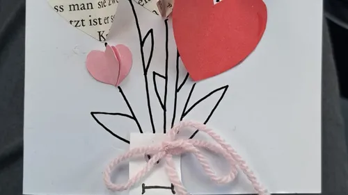 Handgemachte Karte mit Papierherzen und Schleife.