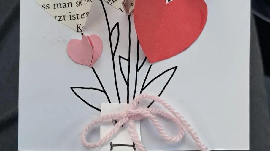 Handgemachte Karte mit Papierherzen und Schleife.