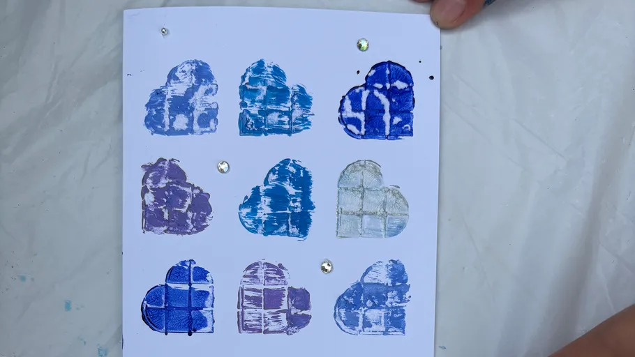 Gestempelte Herzen auf weißer Karte mit Edelsteinen.