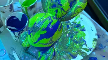 Neon-painted sculpture with paint cups and plate.
