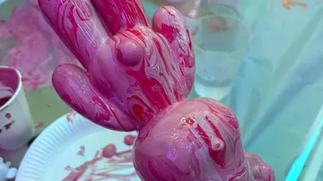 Skulptur-Hand in pinke Farbe eingetaucht.