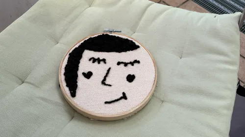 Stickerei eines lächelnden Gesichts auf Kissen.