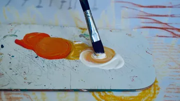 Pinsel mischt Farben auf einer Palette.