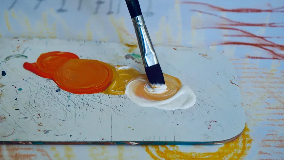 Paintbrush mixing colors on a palette.