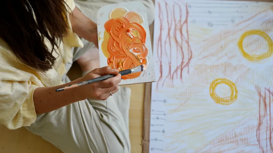 Person painting abstract art with orange tones.