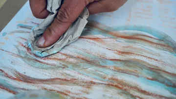 Hand smudging pastel on paper art.