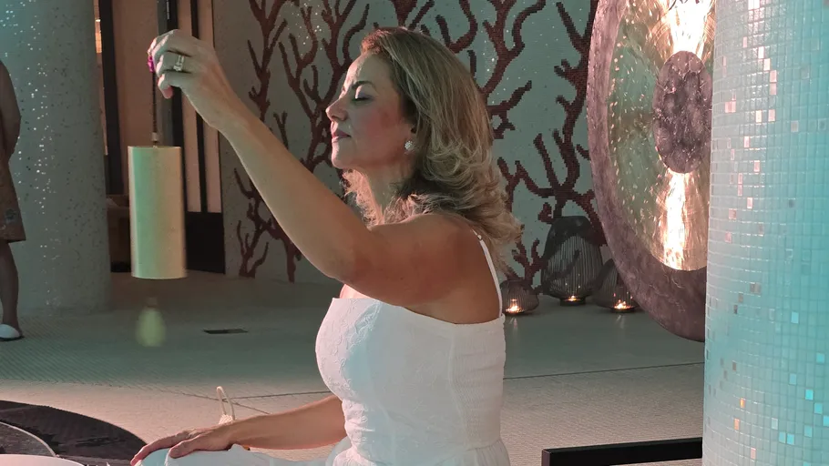 Woman playing singing bowl in serene indoor setting.