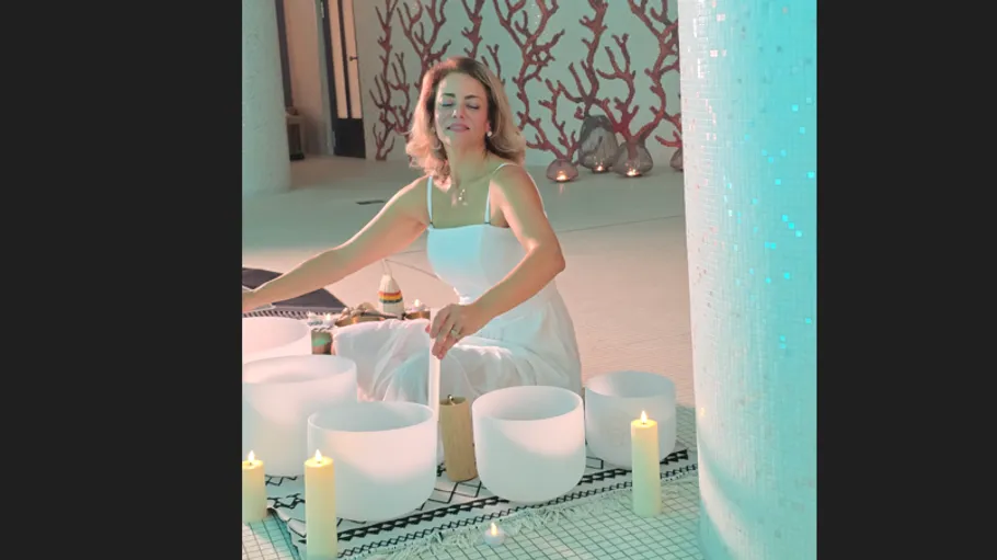Woman playing sound bowls surrounded by candles.