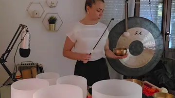 Person playing sound bowls in a room.