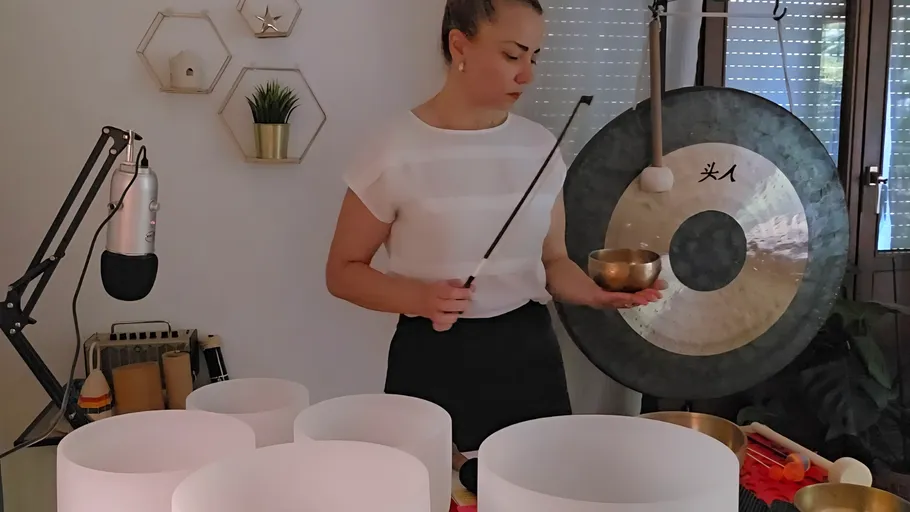 Person spielt Klangschalen in einem Raum.