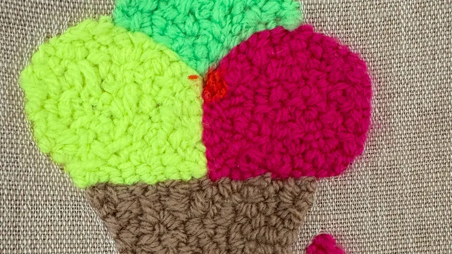 Crocheted ice cream cone on fabric background.