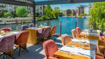 Restaurant with colorful chairs overlooking a river.