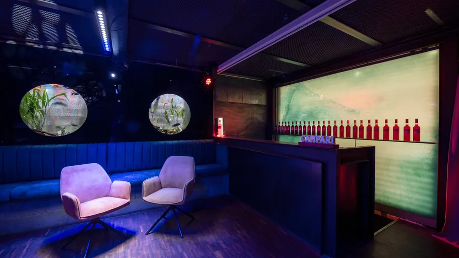 Two chairs facing bar in dim lounge.